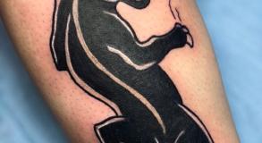 Tatouage panthère old school avec casquette, inspiré du style Peaky Blinders, réalisé par Tamara Chaudesaigues chez Graphicaderme, studio de tatouage à Avignon