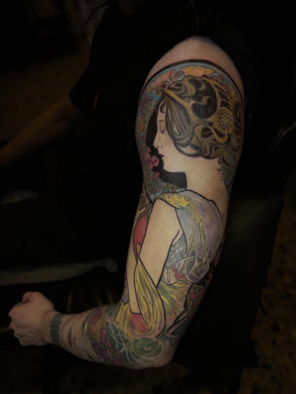 Tatouage bras complet couleur inspiré d’Alphonse Mucha réalisé par Tamara Chaudesaigues chez Graphicaderme à Chaudes-Aigues