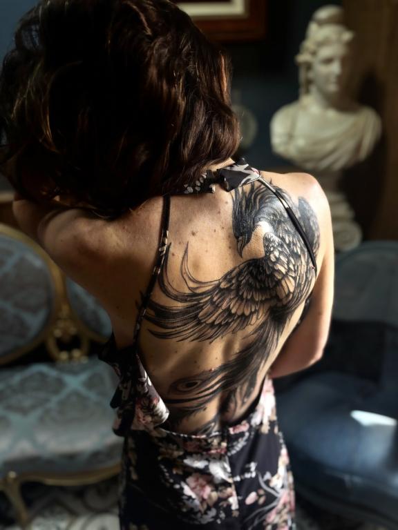 Tatouage phénix noir et gris dans le dos féminin réalisé par Tamara Chaudesaigues chez Graphicaderme à Chaudes-Aigues
