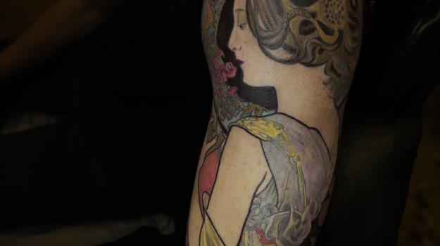 Tatouage Art Nouveau en couleur représentant un portrait féminin inspiré d’Alphonse Mucha sur le bras, réalisé par Tamara Chaudesaigues chez Graphicaderme à Avignon
