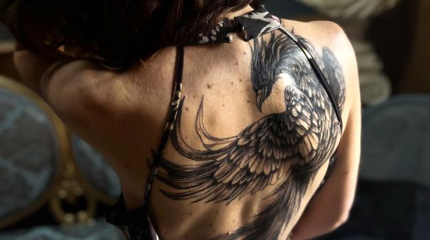 Tatouage phénix noir et gris dans le dos féminin, réalisé par Tamara Chaudesaigues chez Graphicaderme à Avignon, inspiration élégante et mouvement Art Nouveau